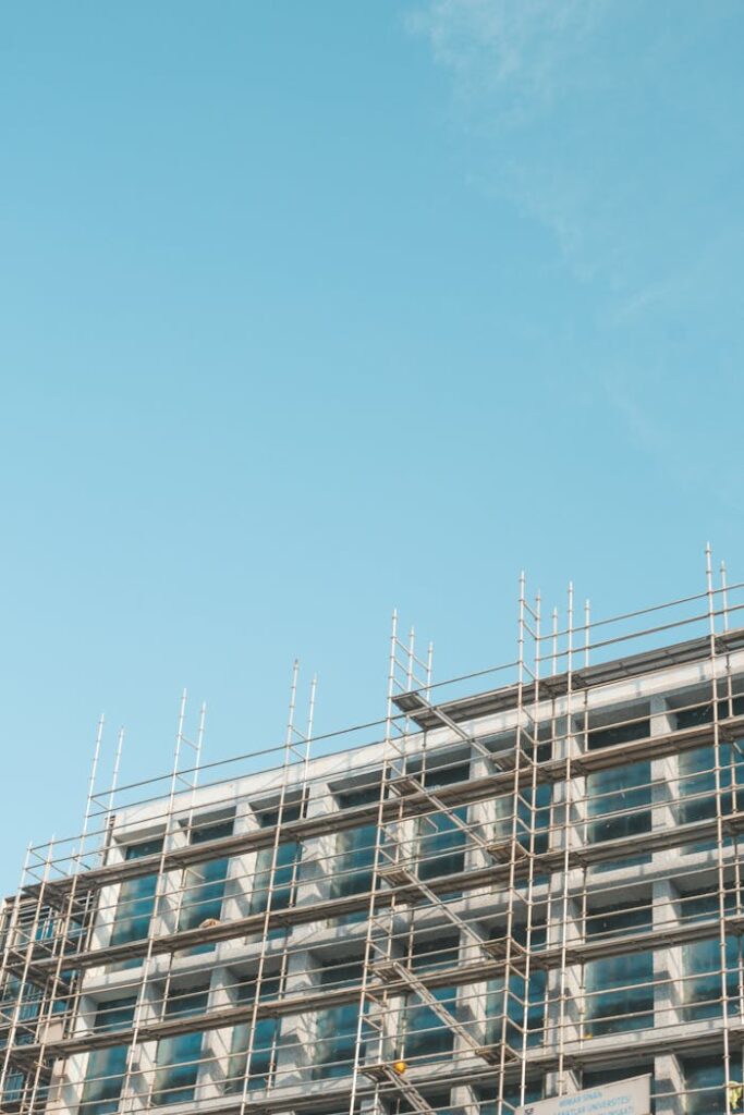 A modern residential building with scaffolding under a clear blue sky, showcasing architectural progress.